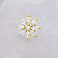 Goldener Piercing Aufsatz in Blütenform mit klaren Kristallen auf hellem Hintergrund